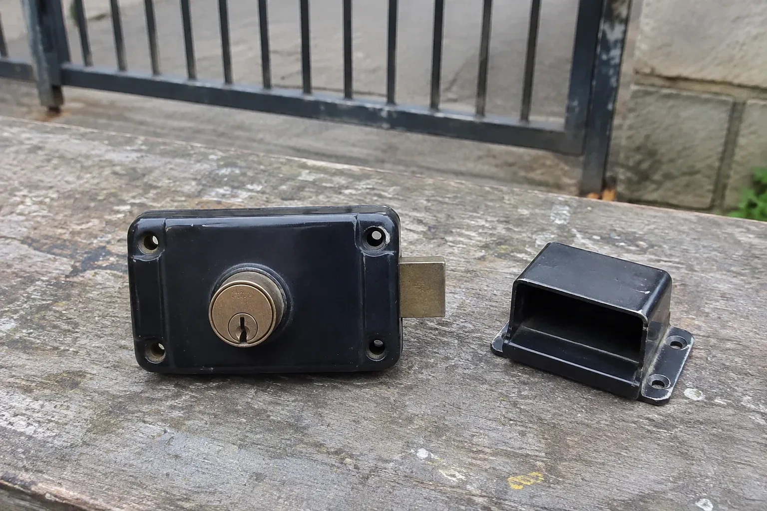 Detached rim gate lock and separate box keeper on an outdoor workbench. — Gate & Building Entry Locks, Caledon